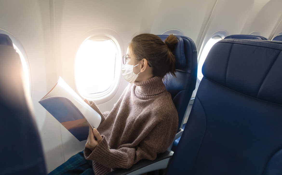 A young woman wearing face mask is traveling on airplane , New normal travel after covid-19 pandemic concept